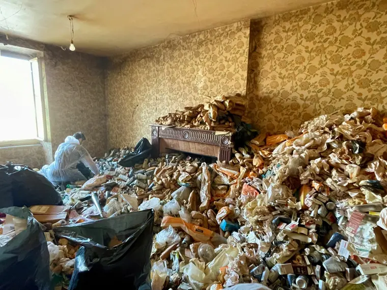 Pièce saturée d'objets accumulés, équipier en combinaison pendant le tri